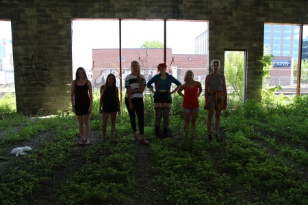 Women-serious-standing-grass-abandoned-building-west-loop